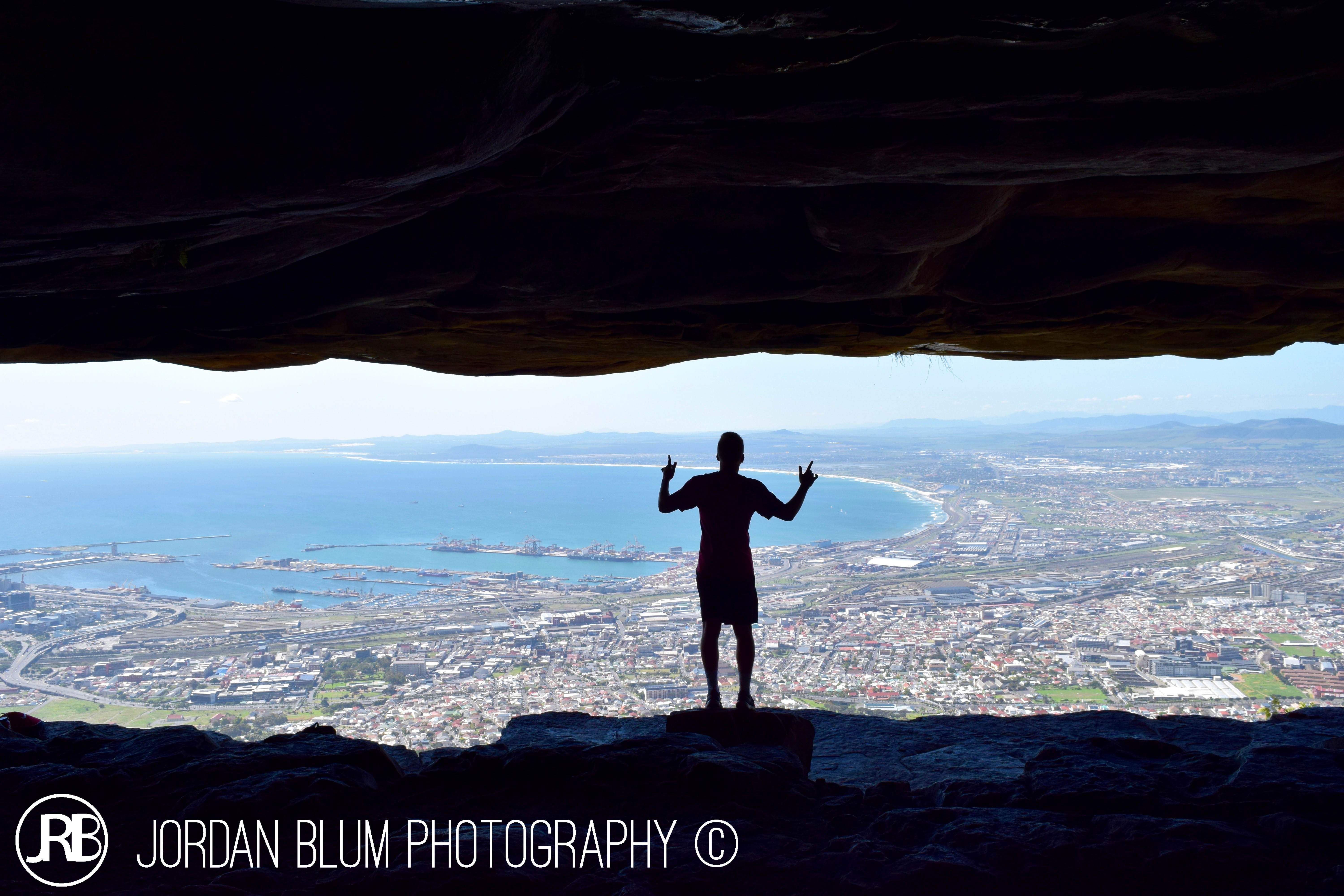 Silhouette in rock cave overlooking Cape Town